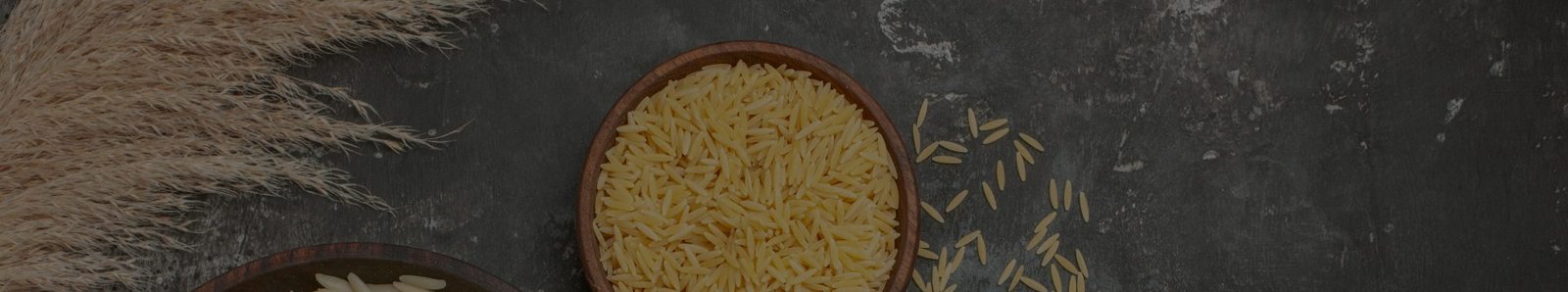 Bowls of raw and cooked Basmati rice on a dark surface